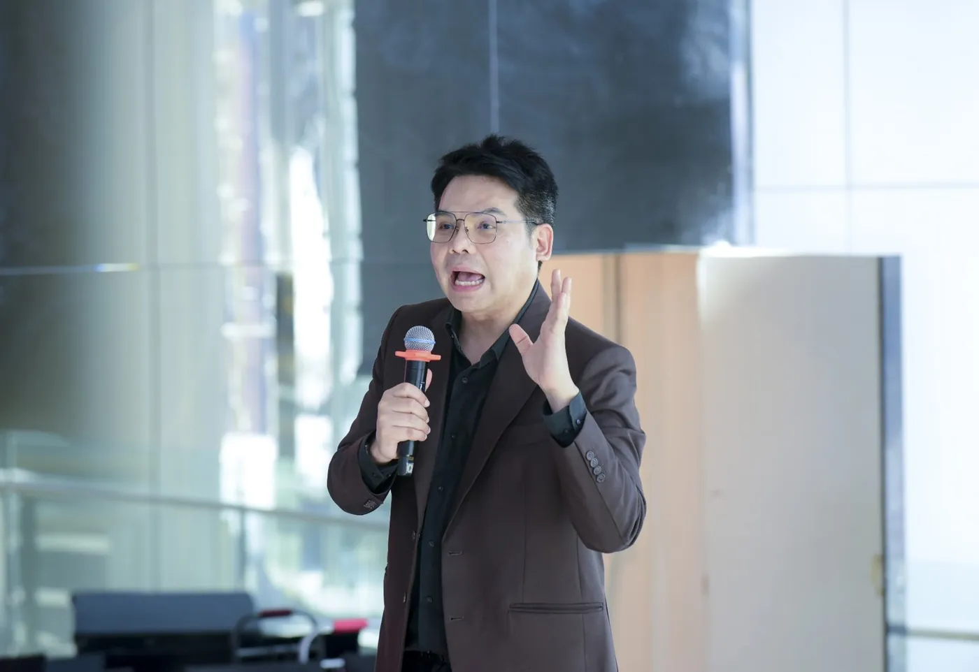 Mr. Ravi Aunyakan, Director, speaking on stage with a microphone